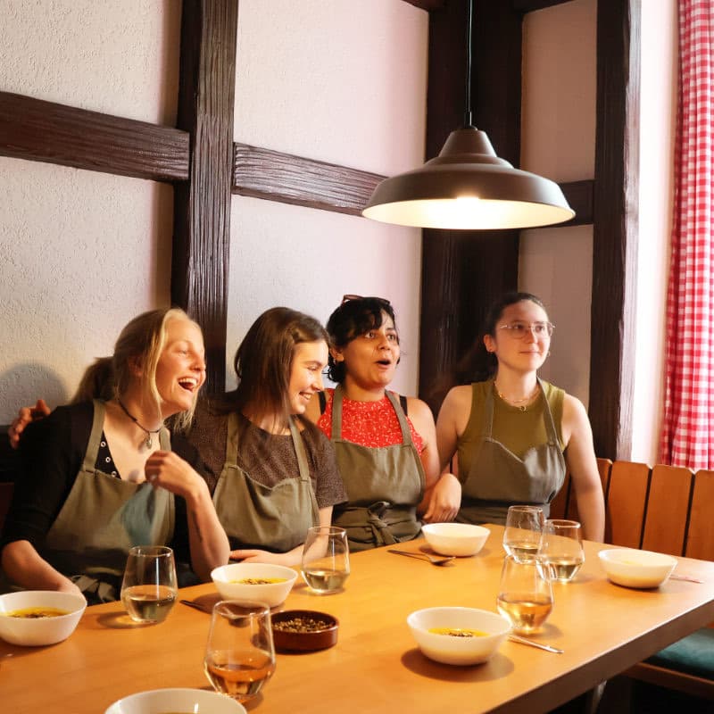 Vier Teilnehmerinnen sitzen lachend am gedeckten Tisch und essen die selbst gekochten Suppen