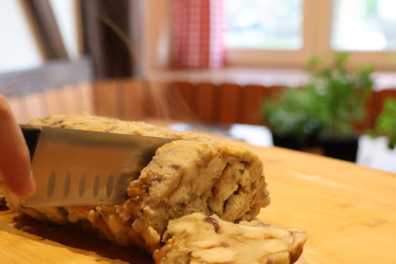 Ein veganer Braten wird auf dem Holzbrett in Scheiben geschnitten